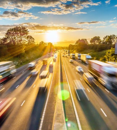 Schwerer Verkehr mit hoher Geschwindigkeit auf einer britischen Autobahn in England bei Sonnenuntergang.